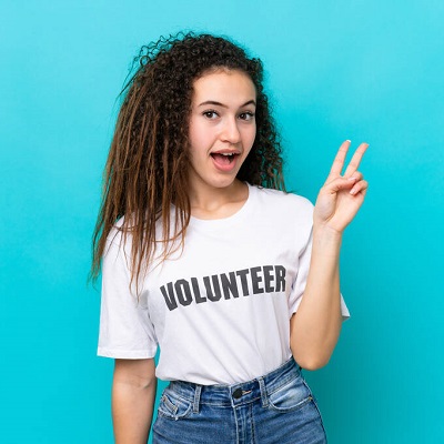 Young Arab volunteer woman isolated on blue background smiling and showing victory sign