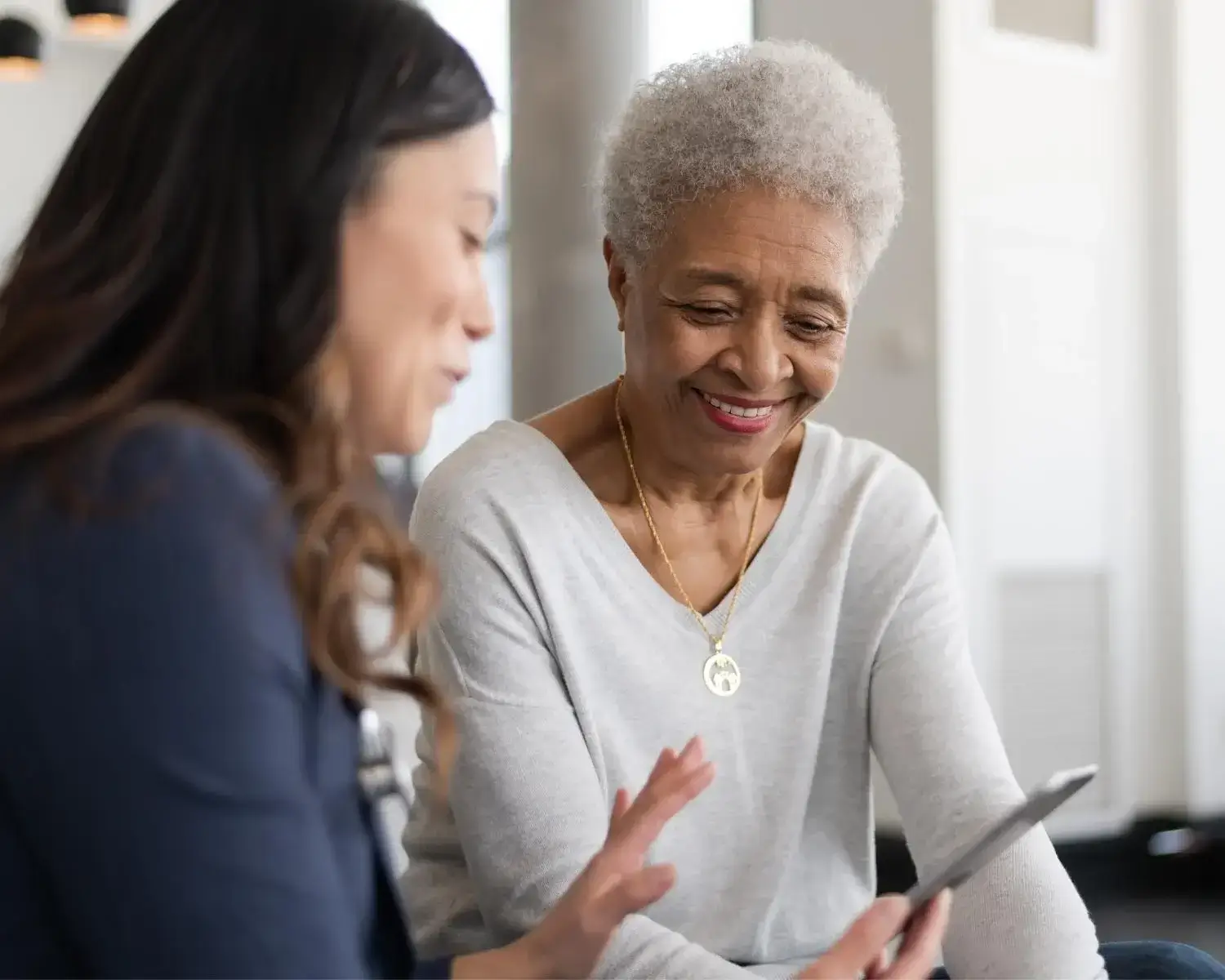healthcare professional talking with older woman while showing ipad (1)
